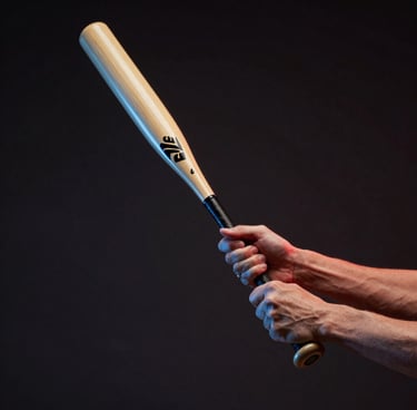 Low-angle dynamic shot of hands gripping a composite baseball bat, dramatic red and blue LED sidelighting, dark background, motion blur on the bat.