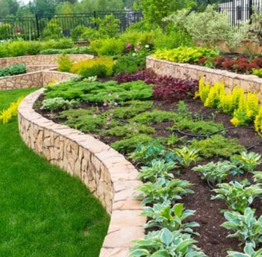 a backyard with a stone wall and plants on the terraces