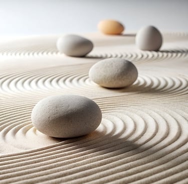 Smooth river stones on a Japanese zen sand garden with raked circular patterns for meditation.