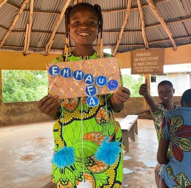 Petite fille qui tient une pancarte avec écrit Emmaüs AFA
