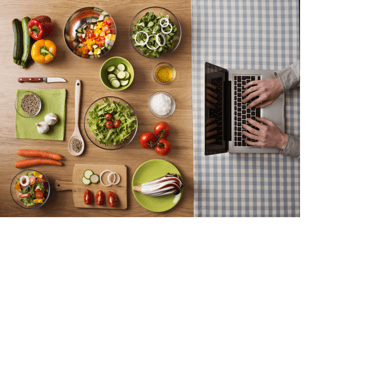 Person typing on laptop at other end of table that displays many dishes/ingredients