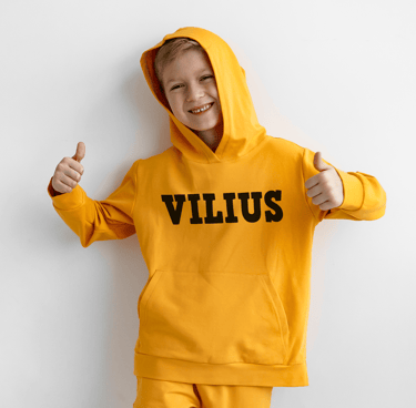 vaikas su geltonu dzemperiu ant kurio yra parasytas vardas Vilius