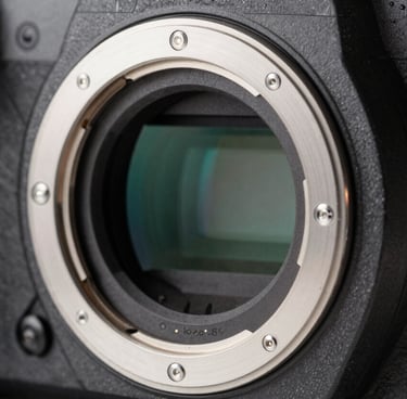 Macro photography of a professional full-frame camera lens mount and internal glass elements, showing intricate mechanical detail and slate gray metallic textures in a North American tech studio.