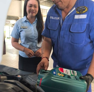 A Suzuki mechanic pouring Castrol Magnatec motor oil into a car engine during a service.