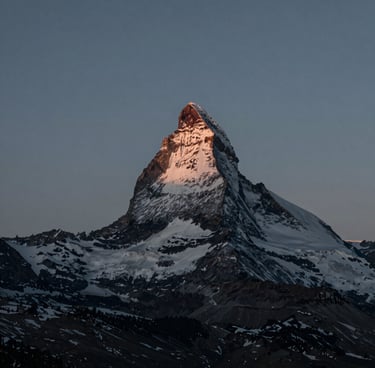 A minimalist landscape photograph of a snow-capped North American mountain peak during the blue hour. The lighting is ethereal and soft. The composition uses a sophisticated palette of dark slate and teal grey, evoking a sense of calm and professional artistry.