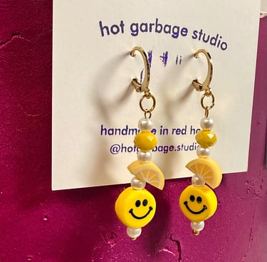 Gold huggie-hoop dangle earrings with yellow smiley faces and beads