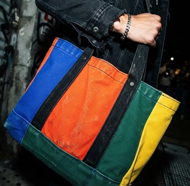 Close-up of heavyweight canvas tote bag texture, vibrant color-blocked design, hard flash lighting, deep shadows, dynamic angle, styled with streetwear.