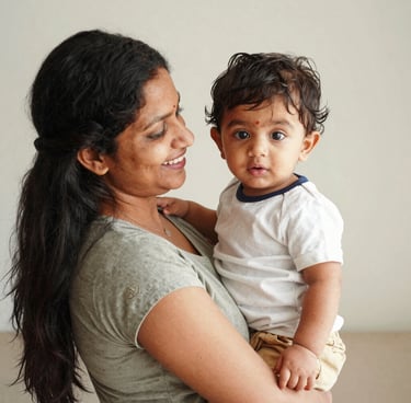 Smiling mother holding her chubby toddler in a bright hospital waiting area.