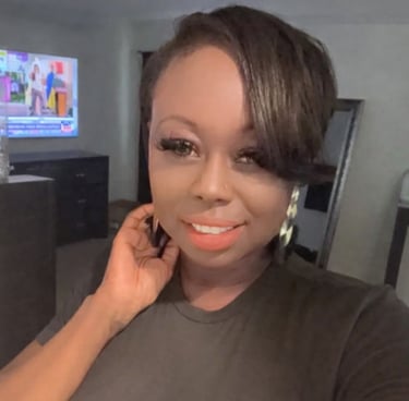 Smiling woman with short side-swept hair, false eyelashes, and hoop earrings in a modern living room.