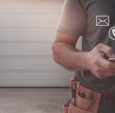 Handyman using a smartphone to contact garage door repair services via email, phone, or chat.