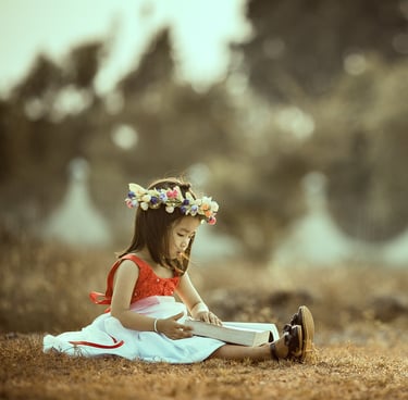 little girl reading a boog outside