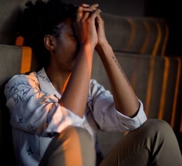 Persona estresada sentada en el suelo con las manos en la cara, lo que representa la salud mental
