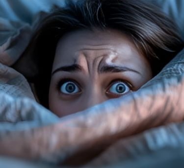 individu sous les couvertures yeux ouverts évoquant des troubles du sommeil