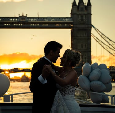 bride and groom kissing on a boat with Tower Bridge, London in their background