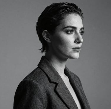 A sophisticated black and white studio portrait of a person with dramatic side lighting, high contrast, slate blue and charcoal tones, elegant and modern Spanish style.