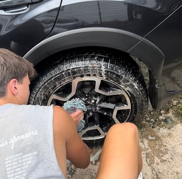 Golden mobile detailing team giving an SUV an exterior wash on its rims and tires