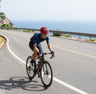 Road cyclist speeding along a coastal route with sea and hills in the background. avvicina il ciclis