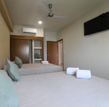 Habitacion con dos camas matrimoniales y un televisor en bungalows a pie de playa en Los Ayala