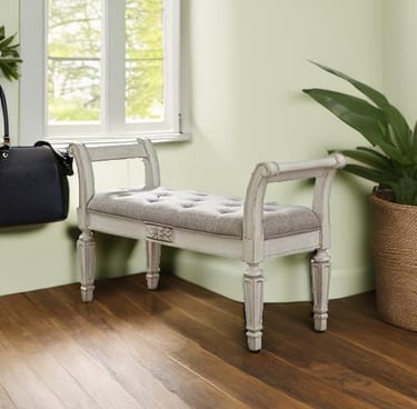 Distressed white tufted upholstered entryway bench with scrolled arms on hardwood floors.