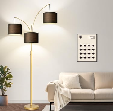 Modern gold 3-light arc floor lamp with black fabric drum shades beside a beige sofa.