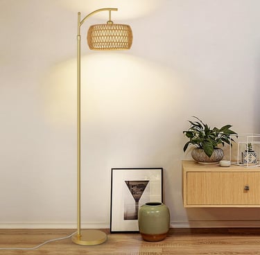Modern gold arch floor lamp with a woven rattan shade in a minimalist living room setting.