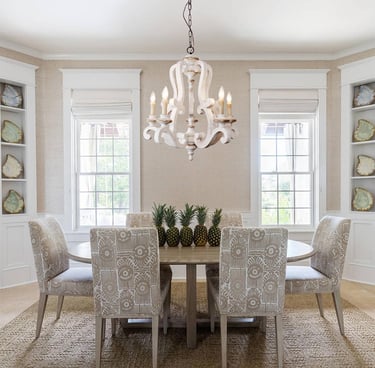 Elegant dining room with a white wooden chandelier and upholstered chairs around a natural wood table.