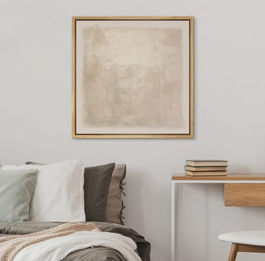 Framed beige abstract wall art hanging above a modern bed and wooden desk in a minimalist bedroom.