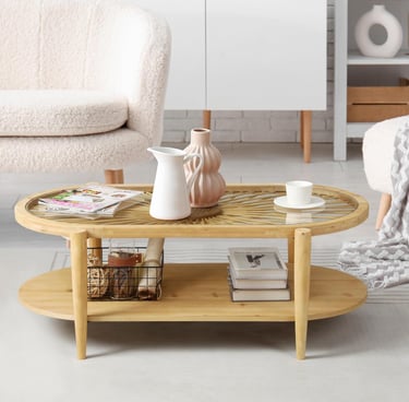 Modern bamboo oval coffee table with a glass top and storage shelf in a bright living room.