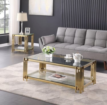 Modern gold glass coffee table and matching end table set in a living room with a grey tufted sofa.