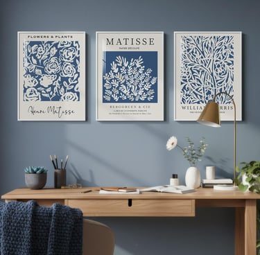 Three blue and white botanical art prints by Matisse and William Morris hung over a wooden desk.