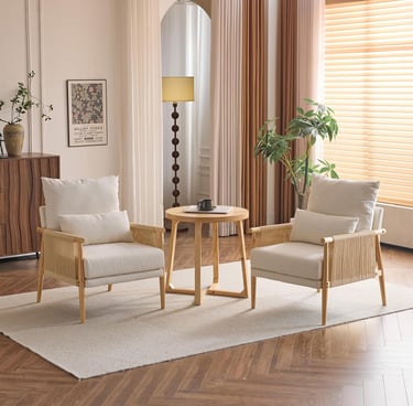 Two modern rattan armchairs with cream cushions and a wooden side table on a rug in a bright living room.