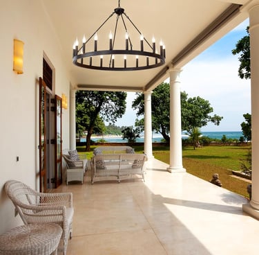 Modern black wagon wheel chandelier hanging over a luxury patio with ocean views.