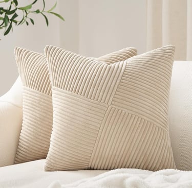 Two beige corduroy decorative throw pillows with a geometric striped pattern on a white sofa.