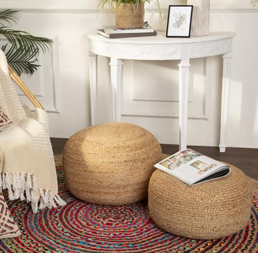 Two round braided jute pouf ottomans on a colorful woven rug in a modern living room setting.