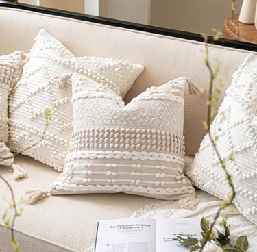 Decorative boho throw pillows with tassels and textured patterns on a neutral cream sofa.