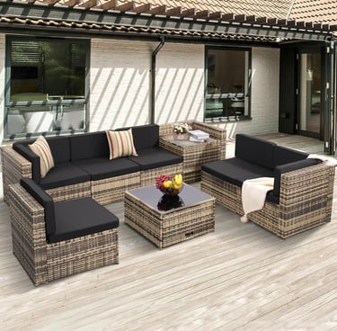 Modern 6-piece wicker patio furniture set with black cushions and glass top coffee table on a wooden deck.