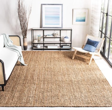 Natural jute area rug in a modern living room with a woven accent chair and console table.