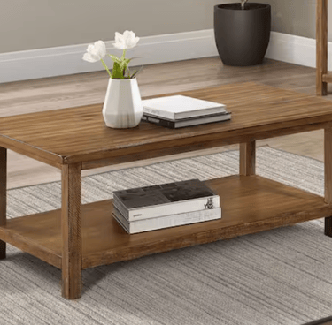 Rustic brown solid wood coffee table with storage shelf on a grey area rug.