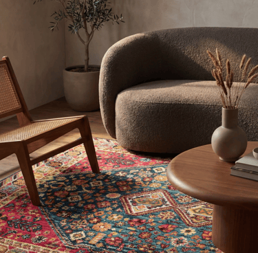 Traditional patterned area rug in a modern living room with bouclé sofa and wooden coffee table.