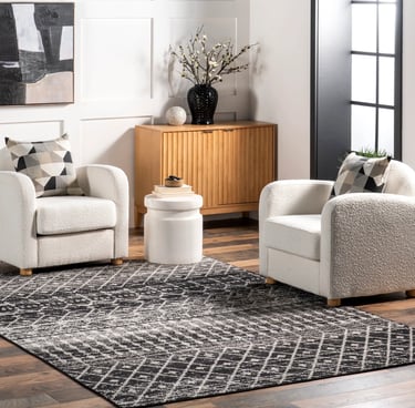 Modern living room featuring a black and charcoal geometric area rug and white boucle swivel chairs.