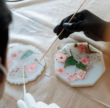 persona poniendole detalles de flores secas a una pieza de resina.