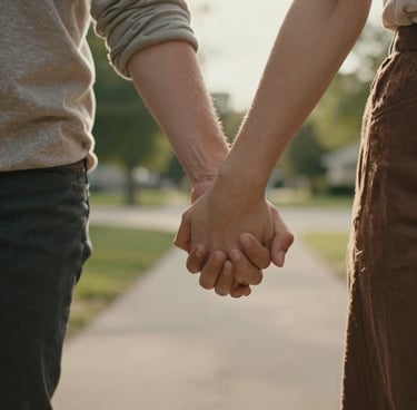 A cinematic close-up of a couple’s hands intertwined while walking through a North American / US suburban park. Warm, soft focus, sun-flares. Natural textures and Warm Brown tones.