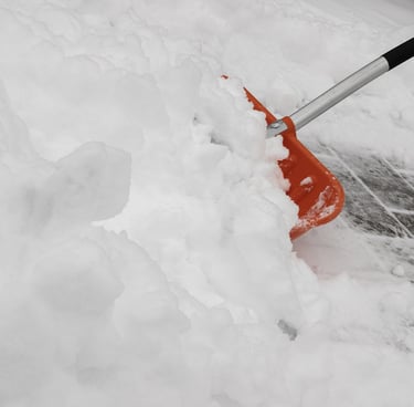 Los Chicos Exterior Solutions team member shoveling snow off a Guelph driveway to keep the property 