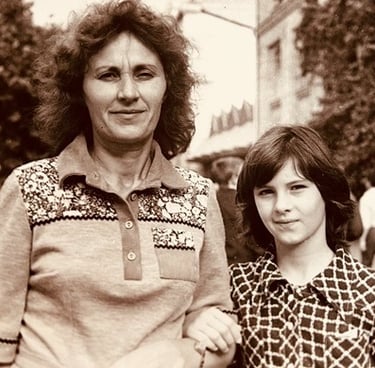 A vintage photo of a woman and a young girl holding hands, smiling gently.