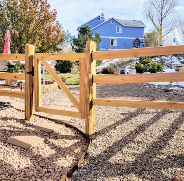 Colorado Springs rustic post fence with blue house behind.