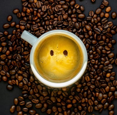 A happy mug of coffee placed amongst freshly roasted coffee beans