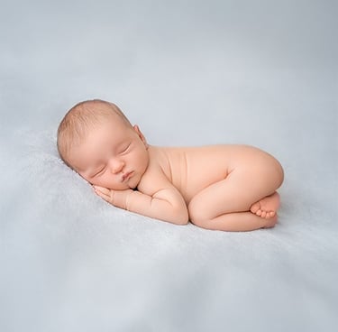 a baby sleeping on a blanket in a studio