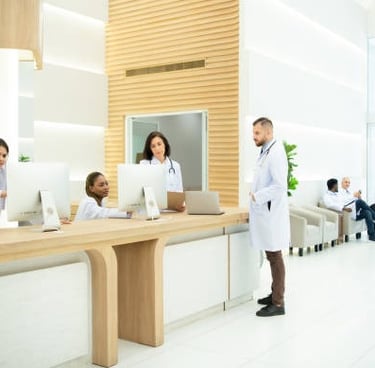 Un médico con bata blanca se encuentra frente al mostrador de recepción de un hospital