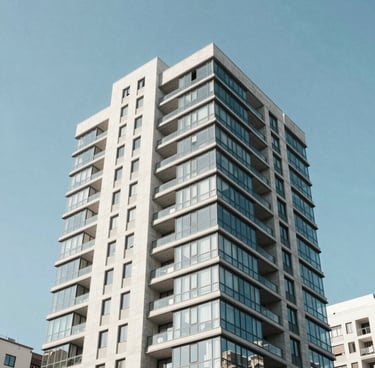 Low-angle architectural photography of a modern residential high-rise with glass and concrete facade in Vitacura, bright crisp morning daylight, clean sharp lines against a clear blue sky, 35mm