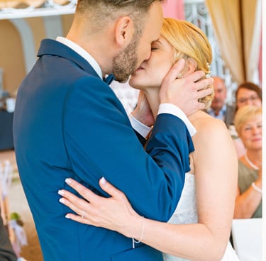 Braut und Bräutigam küssen sich während der Trauung und halten sich dabei liebevoll im Arm.